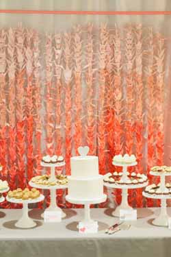 ombre orange paper cranes backdrop behing wedding cake and dessert table