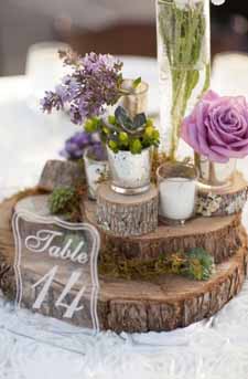 woodland wedding centrepiece ideas tree slices staked up with small vases and mercury silver tea light holders