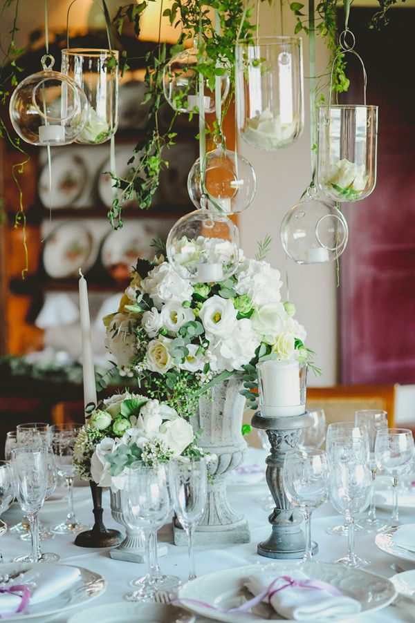 grey urn wedding centrepiece with hanging glass vases and candle holders