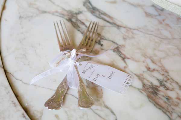 Luggage tag personlaised with the name of the couple tied to the cutlery