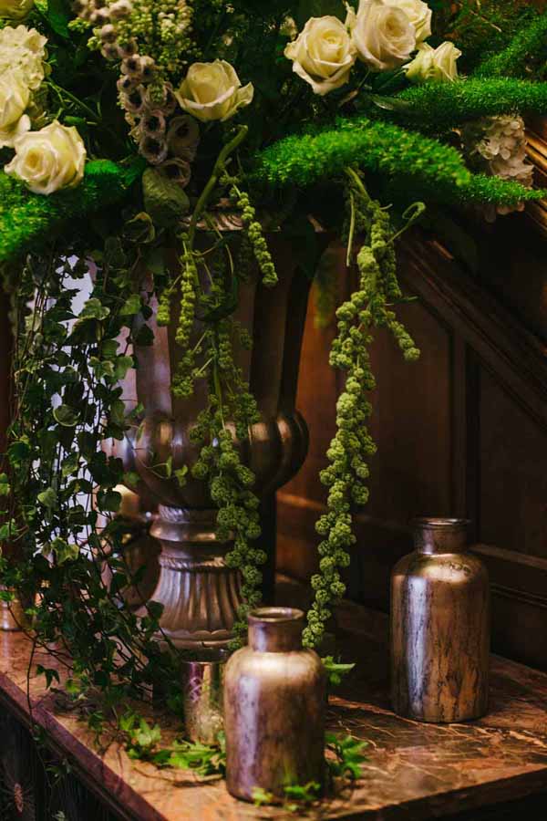 Wedding entrance table flowers large statement urn with gold vases and bottles around the base