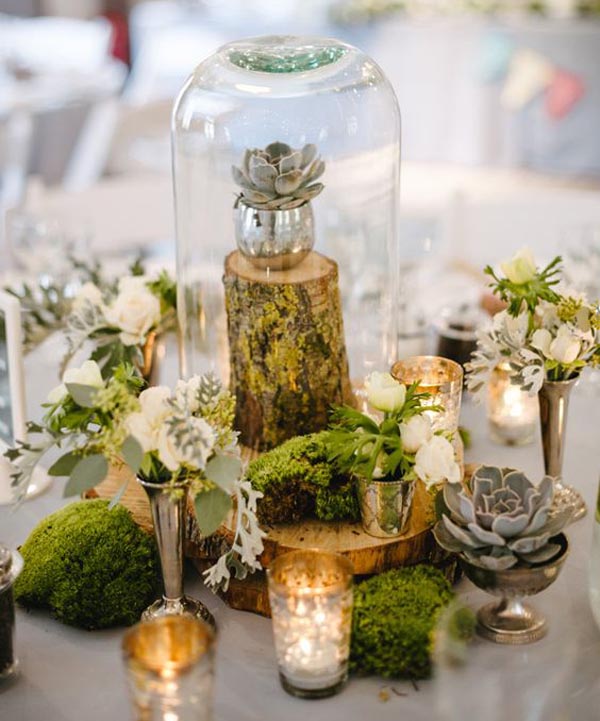 bell jars for wedding centrepieces use different heights and add moss and tree stumps for a rustic look