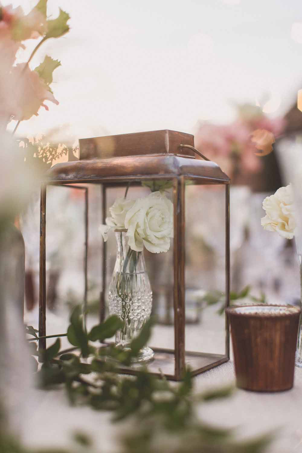 Brass lanterns with small bud vases inside wedding centrepieces