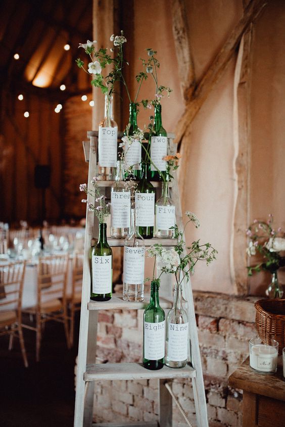 wedding table plans wine bottles with flowers on ladders