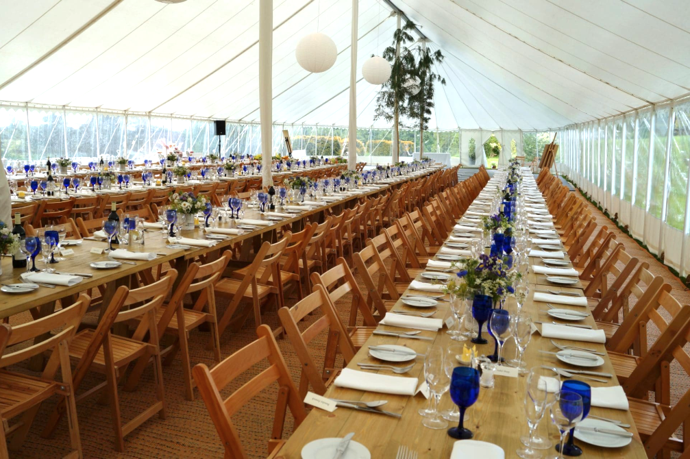 Marquee weddings long wooden tables flowers in small jars Space Intense