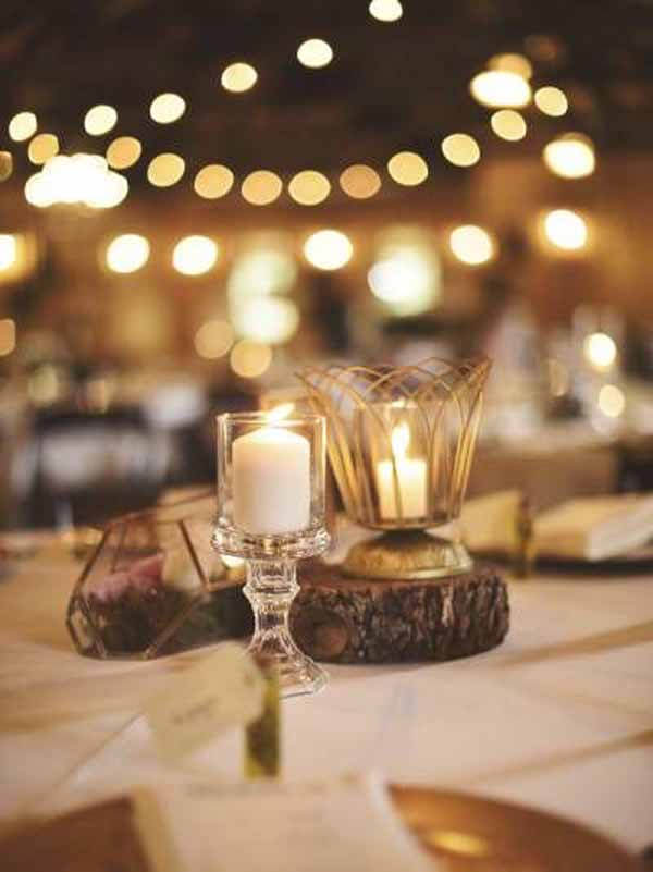 barn wedding centrepieces tree slices with gold lanterns