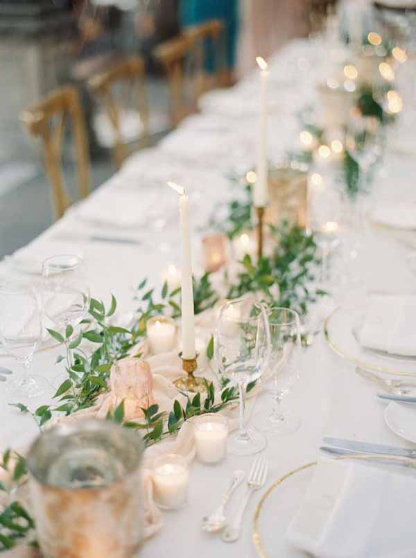 barn wedding with delicate loose laid foliage cream table runners and gold candlesticks