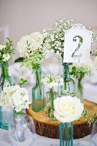 english country garden wedding centrepiece with bottles on wooden tree slice