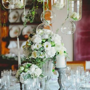 grey urn wedding centrepiece with hanging glass vases and candle holders