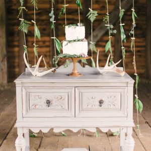foliage pegged on twine makes wedding cake backdrop
