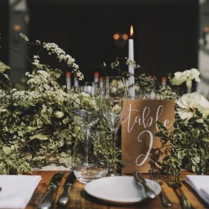 long wedding table garlands brass candlesticks and brown table numbers